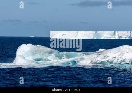 Antarktis, Südliche Orkney-Inseln. Eisberg mit großem tabellarischem Eisberg in der Ferne, der in der Nähe der Orkneys schwimmt. Stockfoto