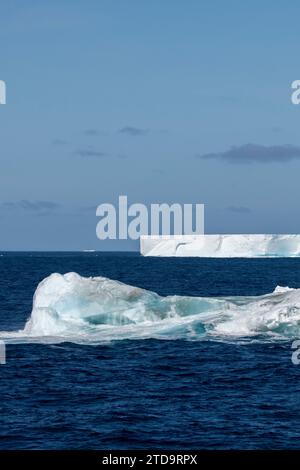 Antarktis, Südliche Orkney-Inseln. Eisberg mit großem tabellarischem Eisberg in der Ferne, der in der Nähe der Orkneys schwimmt. Stockfoto