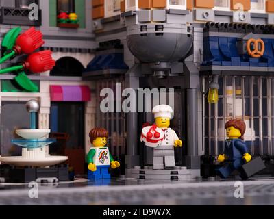 Tambow, Russische Föderation - 07. Januar 2023 Ein Lego-Konditor mit einem Kuchen, der vor die Haustür einer Bäckerei kommt. Junge und Geschäftsfrau Minifig Stockfoto