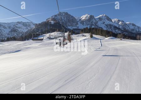 Sessellift und gut vorbereitete Skiabfahrt in einem Skigebiet in den verschneiten Bergen. Österreich Stockfoto