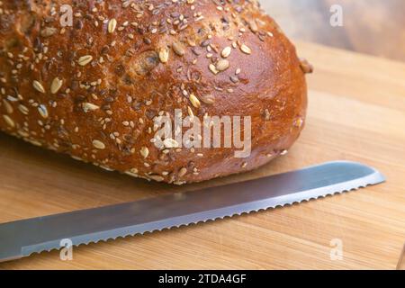 Frisch gebackenes Mehrkornbrot auf einem Schneidebrett mit einem Messer Stockfoto