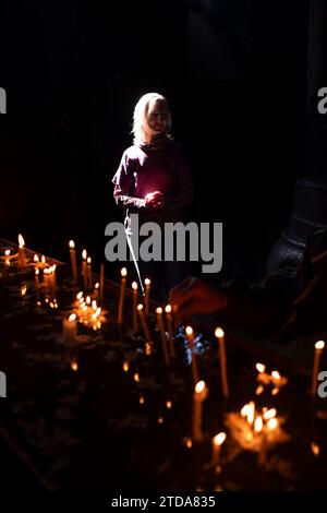 Eine Frau steht im Tempel neben brennenden Kerzen. Stockfoto