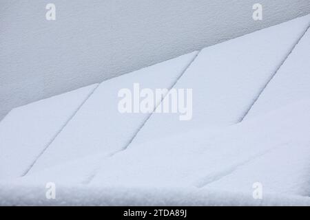 Schneebedeckte Sonnenkollektoren auf einer Garage: Winterfeste erneuerbare Energien Stockfoto