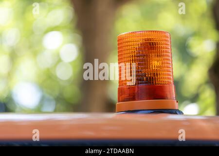 Erhöhte Sicherheit: Leuchtendes orangefarbenes Warnlicht auf dem Landschaftsgestaltungsfahrzeug inmitten eines unscharfen Hintergrunds Stockfoto