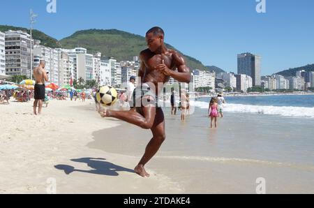 Rio de Janeiro, Brasilien. Dezember 2023. Ein junger Mann tritt mit Freunden am Copacabana Beach in Rio de Janeiro, Brasilien, einen Fußball, während sich Frühaufsteher durch den goldenen Sand winden und Fitness und Ruhe verbinden, wenn die Stadt erwacht. (Credit Image: © Bob Karp/ZUMA Press Wire) NUR REDAKTIONELLE VERWENDUNG! Nicht für kommerzielle ZWECKE! Stockfoto