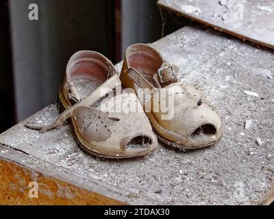 Ein paar alte, abgenutzte Sandalen, die mit Staub bedeckt sind. Stockfoto