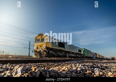 Profilansicht eines Güterzugs mit Intermodalwagen voller Container für den Import und Export auf einem Hof oder Anschlussgleisen Stockfoto