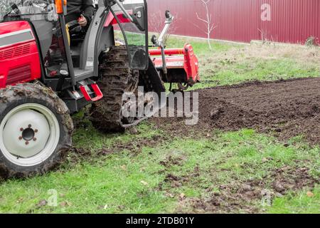 Ein Minitraktor mit einer Fräsmaschine pflügt an einem Herbsttag auf einem landwirtschaftlichen Feld den Boden. Stockfoto