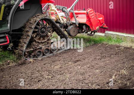 Ein Minitraktor mit einer Fräsmaschine pflügt an einem Herbsttag auf einem landwirtschaftlichen Feld den Boden. Stockfoto