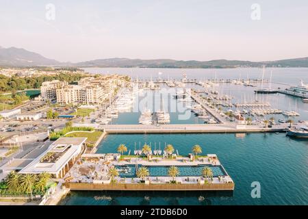 Swimmingpool auf einem breiten Dock mit verankerten Yachten eines luxuriösen Yachthafens. Porto, Montenegro. Drohne Stockfoto