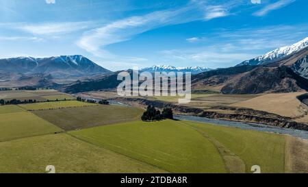 Der Fluss Porters fließt durch ein ländliches landwirtschaftliches Tal, das von schneebedeckten Gebirgszügen im alpinen Hochland begrenzt wird Stockfoto