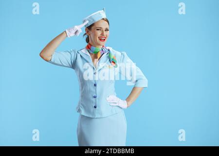 Lächelnde elegante weibliche Lufthostess auf blauem Hintergrund in blauen Uniformen-Salutinen. Stockfoto