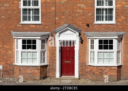 Traditionelles typisches englisches georgianisches Stadthaus mit einer offenen weißen georgianischen Veranda und einer roten Eingangstür. New Alresford, England Stockfoto