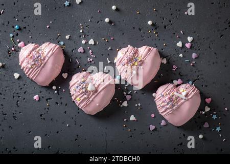 Leckere und romantische Mono-Portion zum valentinstag als besonderer Snack. Rosafarbene Mono-Portion in Herzform mit Streuseln. Stockfoto