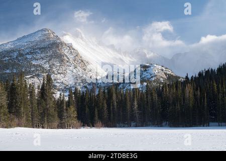 Dramatischer Winterwettersturm auf dem 14.259 Fuß langen Longs Peak aus dem gefrorenen, schneebedeckten Bear Lake. Stockfoto