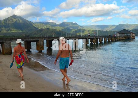 Ein erwachsenes Paar waten im Sommer an einem Urlaubstag in Hanalei, Kauai, Hawaii, in den Gewässern in der Nähe des Piers Stockfoto