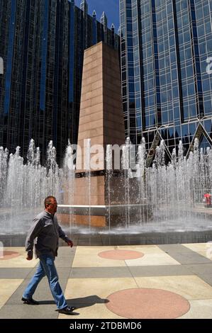 Ein erwachsener Mann spaziert während der Mittagszeit durch den öffentlichen Raum des PPG Place in Pittsburgh, Pennsylvania Stockfoto