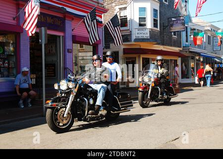 An einem sonnigen Sommerferientag tummeln sich zwei Motorräder durch die historische Innenstadt von Provincetown, Cape Cod, Massachusetts Stockfoto