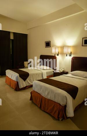 Hotelzimmer mit zwei Einzelbetten, gedämpfter Innenbeleuchtung Stockfoto