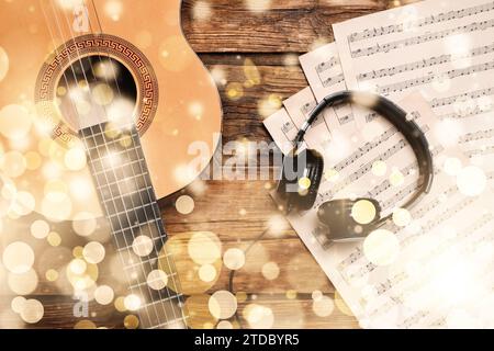 Weihnachtsmusik und Neujahrsmusik. Kopfhörer und verschiedene Musikinstrumente auf hölzernem Hintergrund, Bokeh-Effekt Stockfoto