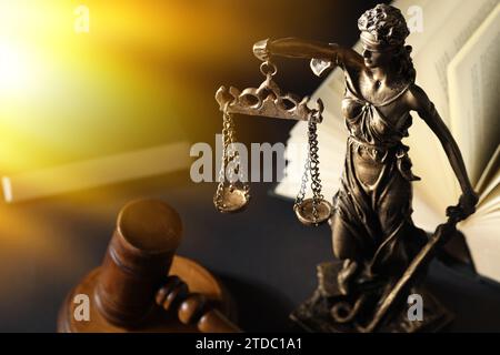Symbol für eine gerechte Behandlung nach dem Gesetz. Statue von Lady Justice, Hammer und Buch auf schwarzem Tisch, Platz für Text Stockfoto