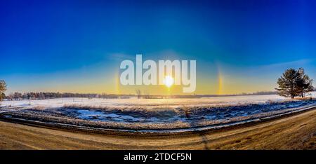 Atmosphärisches optisches Phänomen Sonnenhunde am Morgen über einem Schneefeld. Stockfoto