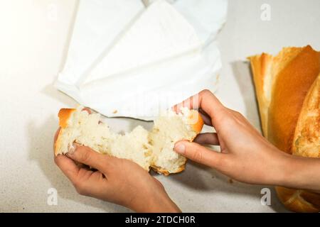 Frau Hände, die frisch gebackenes Brot brechen, um Käse-Sandwich für Kinder als Snack zu machen Stockfoto