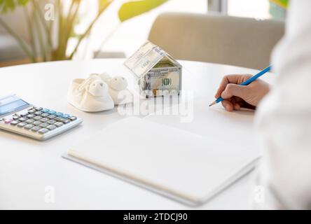 Eine Frau, die sich auf die Geburt vorbereitet, macht die Berechnungen für den Kauf eines Hauses. Stockfoto
