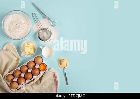 Zusammensetzung der Zutaten zum Backen auf farbigem Papier (Eier, Mehl, Butter, Milch und Werkzeuge) Stockfoto