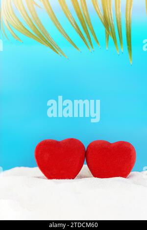 Rote Herzen auf Sand mit Palme vom Strand hinter dem Meer. Valentinstag, Hochzeit, Flitterwochen, Urlaub, Vorschlag. Kopierbereich Stockfoto