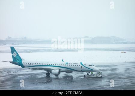 Flugzeuge, die bei einem Schneesturm auf die Landebahn gezogen werden Stockfoto