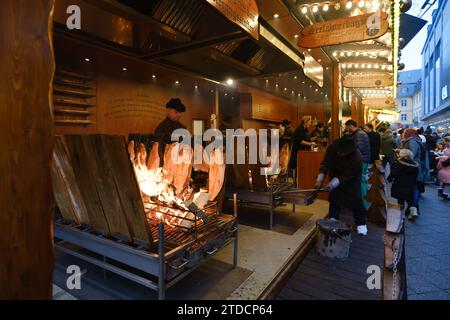 Bonn - 16. Dezember 2023 : Blick auf geflammten Lachs über Buchenholz auf dem Bonner Weihnachtsmarkt Stockfoto