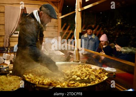 Köche bereiten Würstchen und andere Artikel an den Essensständen im Freien auf dem Tallinner Weihnachtsmarkt in der mittelalterlichen Altstadt von Tallinn, Estland, zu Stockfoto