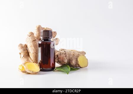 Natürliches ätherisches Ingweröl in einer medizinischen Flasche auf dem Hintergrund von Ingwerwurzel und -Scheiben. Das Konzept der Feuchtigkeitspflege der Haut. Mock-Up. Stockfoto