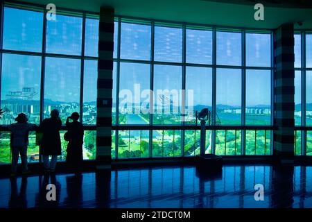 Hanam City, Südkorea - 1. Oktober 2023: Besucher auf dem Oberdeck des Hanam Union Tower beobachten den Misa Boat Race Park durch den hohen wraparound wi Stockfoto