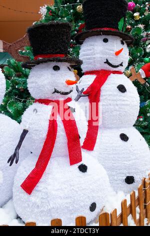 Zwei Schneemänner in der Nähe von Tannenbaum in vertikaler Zusammensetzung Stockfoto