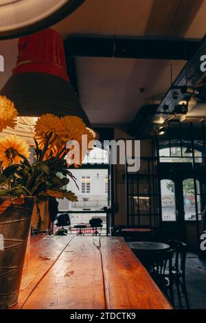 Cafe im Loft-Stil. Modernes Café-Design. Leeres Café mit großen Fenstern und Blumen auf Holztisch. Gastronomie. Gemütliches Restaurant-Design. Stockfoto