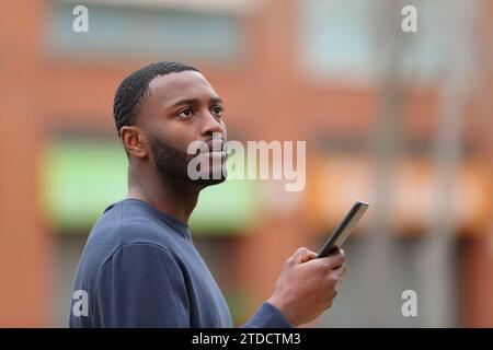 Der verlorene Schwarze sucht den Standort auf dem Smartphone auf der Straße Stockfoto