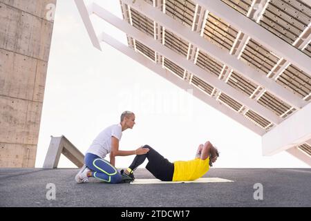Trainer hilft Senioren-Sportlern beim abs-Workout Stockfoto