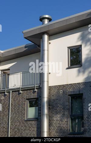 Dickes Edelstahl-Auspuffrohr an der Fassade eines Wohngebäudes Stockfoto