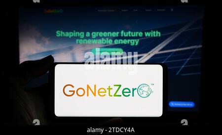 Person, die ein Smartphone mit dem Logo des singapurischen CO2-Management-Unternehmens GoNetZero vor der Website hält. Schwerpunkt auf dem Display des Telefons. Stockfoto