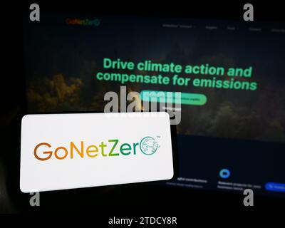 Person, die ein Mobiltelefon mit dem Logo des singapurischen CO2-Unternehmens GoNetZero vor der Business-Webseite hält. Schwerpunkt auf dem Display des Telefons. Stockfoto