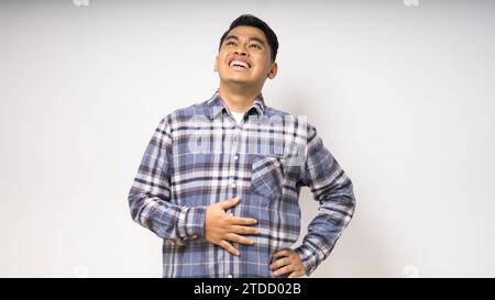 Asiatische Asiatin lächelt stolz, während sie nach oben auf weißem Hintergrund blickt. studio-Aufnahme Stockfoto