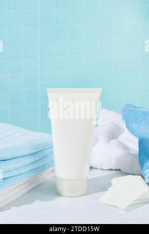 Nahaufnahme einer Tube Gesichtsreiniger mit Handtüchern und Wattepads auf blauem und weißem Hintergrund. Konzept der hautreinigenden Kosmetik. Stockfoto