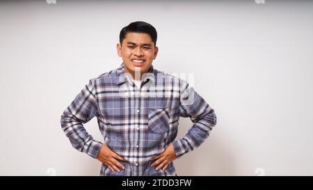 Junger asiatischer Mann mit schmerzhaften Magenschmerzen auf weißem Hintergrund Stockfoto