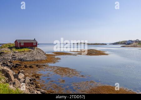 Ein einsamer, klassischer roter Rorbu thront auf Stelzen auf einem glatten, vom Meer polierten, felsigen Ufer der Nordsee auf den Lofoten in Norwegen Stockfoto