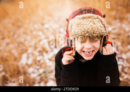 Kleiner Junge lächelnd mit Hut vor Herbstlaub Stockfoto