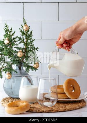 Die Hand einer Frau gießt Milch in ein Glas Stockfoto
