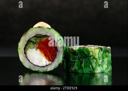 Japanische Sushi-Rollen in Chuka-Salat auf dunklem Hintergrund mit Re Stockfoto