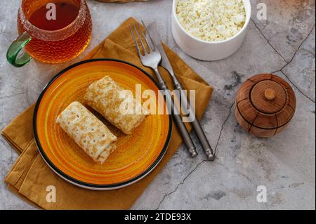 Pfannkuchen mit Hüttenkäse auf einem Teller. Tee in einer Tasse. Stockfoto